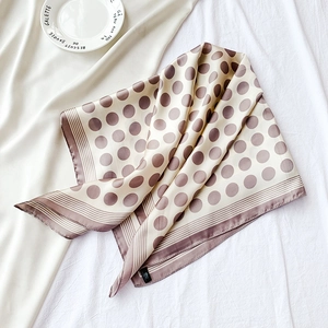Détail d'un foulard en soie avec motifs à pois et bordures rayées en beige et marron