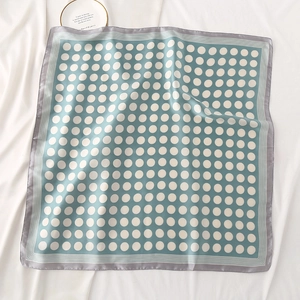 Détail d'un foulard en satin de soie à pois blancs sur fond vert menthe pour le style