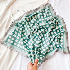 Gros plan d'un foulard en soie à pois verts et blancs avec des bords rayés