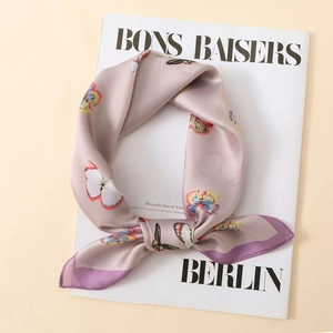 Detailed close-up of light purple satin scarf with colorful butterfly print and silk texture