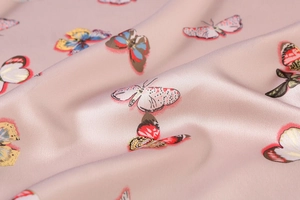 Macro shot of satin silk scarf featuring colorful butterfly patterns on soft pink fabric