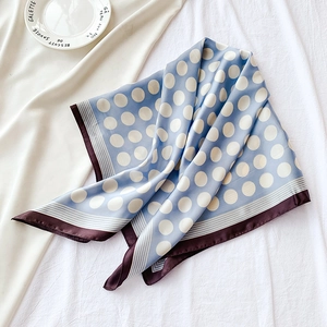 Gros plan détaillé d'un foulard en soie à pois bleu clair avec bordure marron sur blanc