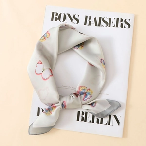 Detailed view of light gray satin scarf with vibrant butterfly prints and silky texture