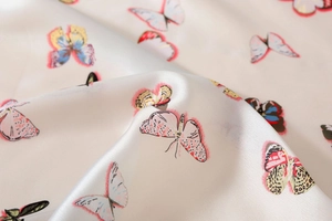 Detailed macro view of the smooth satin silk fabric featuring colorful butterfly prints