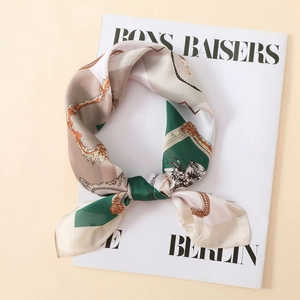 Detailed macro view of smooth satin scarf with vintage gold chains and emerald patterns