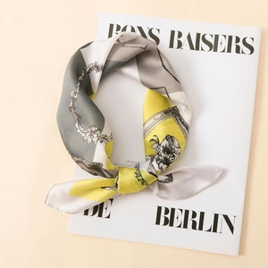 Close-up of printed satin silk scarf featuring vintage chain patterns and vibrant yellow hues