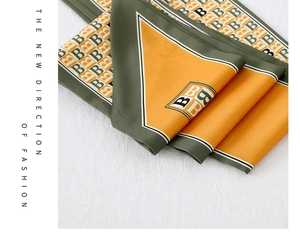 Macro detail of silk scarf showing olive green and orange geometric B patterns
