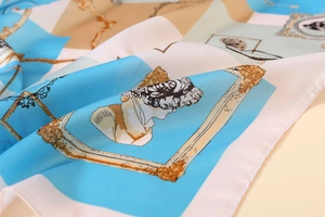 Close-up of elegant satin scarf with vintage plaster statues and golden chain patterns