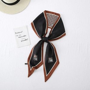 Elegant black and brown silk scarf with B-pattern print tied in a neat bow knot