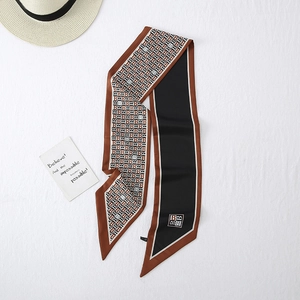 Detail view of the narrow silk scarf with elegant B-letter print and caramel brown edges
