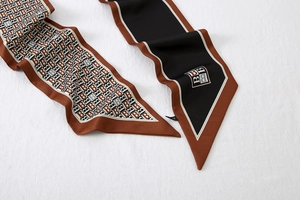 Detail of a brown and black B-monogram silk twilly scarf showing elegant satin texture