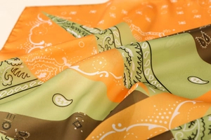 Detail of satin scarf with paisley prints and geometric patterns in orange and green