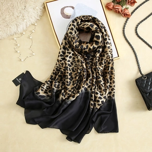 Detail of elegant leopard print silk scarf with luxury accessories and brand tag