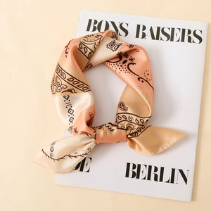 Detail of satin paisley scarf with champagne orange tones tied over a magazine