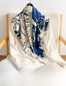 Détail d'un foulard en soie élégant aux motifs de roses bleu marine et beige sur chemisier