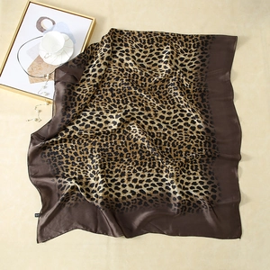 Detailed macro shot of leopard print faux silk scarf showing smooth satin texture and border
