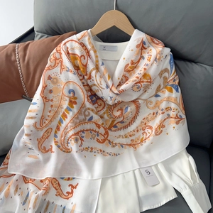 Detailed macro view of white scarf featuring vibrant orange and blue paisley print patterns