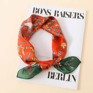 Close-up of vintage floral satin scarf with orange and green patterns on magazine
