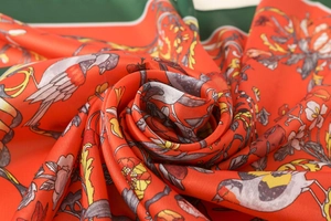 Macro detail of satin scarf showing floral bird print and smooth silk-like texture