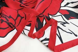 Gros plan détaillé du foulard en soie aux motifs floraux rouges et au fini satiné brillant