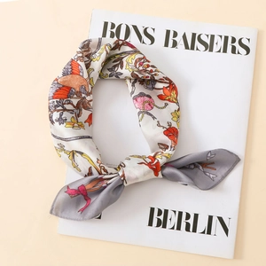 Close-up of satin silk scarf with vintage bird and floral prints on a white magazine