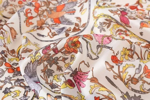 Close-up of floral bird print on smooth satin scarf fabric showing luxury silk texture