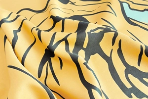 Détail d'un foulard en soie sergé montrant la texture jaune et le motif rose noir