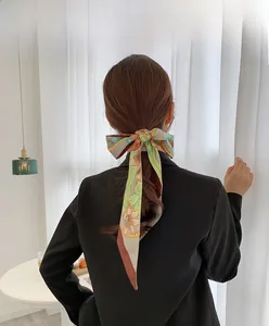 Close-up of a floral satin skinny scarf tied as a hair accessory on a model back view