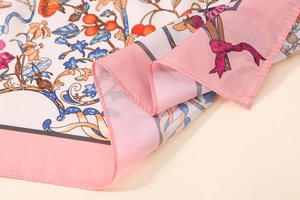 Detailed macro view of satin printed scarf showing delicate floral patterns and pink border