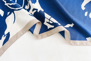 Détail d'un foulard en soie bleu marine à imprimé floral blanc et texture en sergé fin