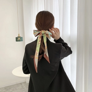 Floral print long skinny silk scarf tied on ponytail in a minimalist interior setting