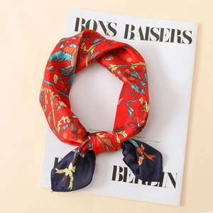 Detailed shot of red floral silk scarf with bird motifs and navy blue border detail