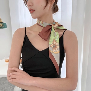 Close-up of floral skinny scarf tied with a sparkling metal buckle in a French style