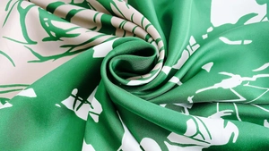 Gros plan d'un foulard en soie sergé vert et crème montrant sa texture et son motif rose