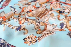 Close-up of sky blue satin scarf featuring gold Baroque patterns and floral prints