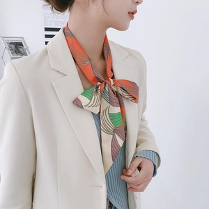 Detail of floral skinny silk scarf styled as an elegant accessory with a white blazer