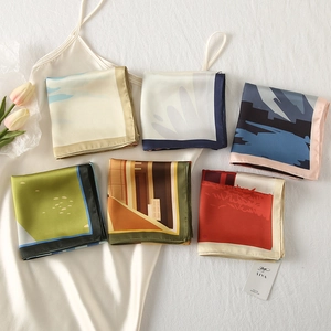 Macro shot of assorted satin silk square scarves with elegant floral and abstract prints