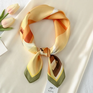 Elegant geometric patterned satin silk scarf in warm yellow and orange with chic necktie knot