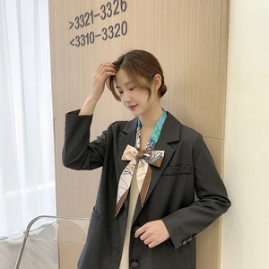 Floral skinny silk scarf tied as a bow on a black blazer with abstract blue and brown patterns