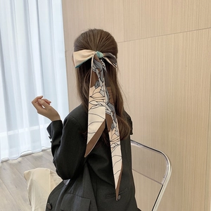 Detailed view of a long floral silk scarf tied elegantly around a ponytail in a bow