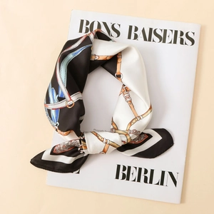 Detail of satin square scarf with gold chain print and black border on a magazine