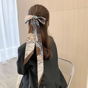 Detailed back view of a long floral silk hair scarf ribbon styled as a bow on a hairstyle