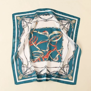 Detailed close-up of teal and gold equestrian motif on smooth satin silk scarf surface