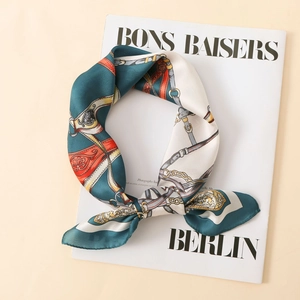 Macro detail of satin silk scarf featuring vintage horse harness print and chain patterns