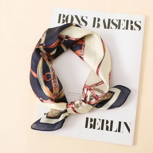 Close-up of satin silk scarf with vintage equestrian chain and floral prints