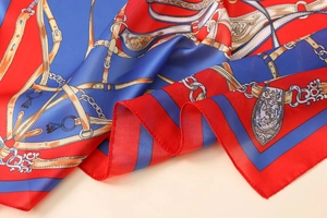 Close-up of satin scarf with red and blue equestrian print and metal chain patterns