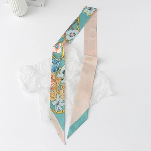 Detailed close-up of blue floral skinny silk scarf with gold chain patterns on a white background