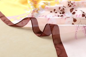 Close-up of soft floral print silk scarf featuring pink leaves and brown stitched edges