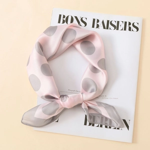 Detail of pink satin scarf with grey polka dots tied in a bow on a fashion magazine