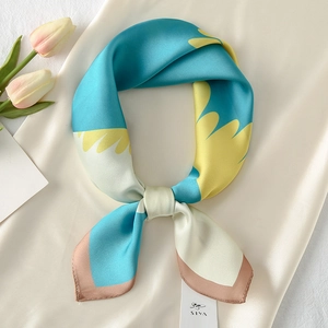 Close-up of square satin scarf with abstract patterns, tied in a knot on silk fabric